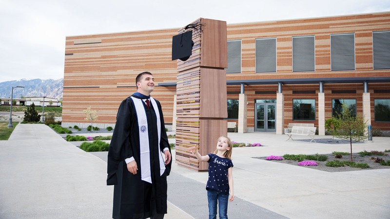 A man tosses his graduation cap with his daughter.